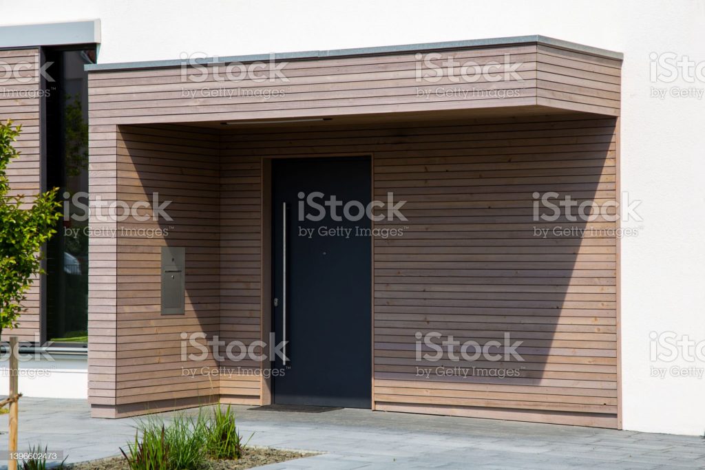 Beautiful entrance to a new residential house with modern front door and wooden panels